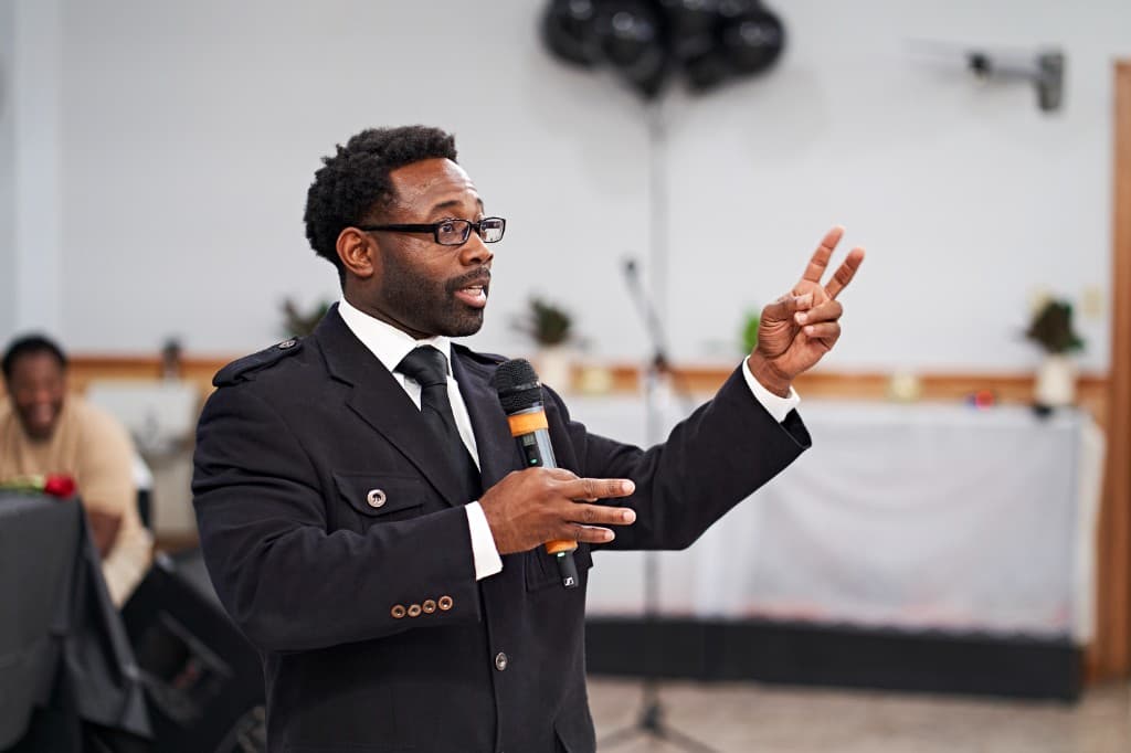 Alonzo Waheed Sr. speaking on stage with a microphone